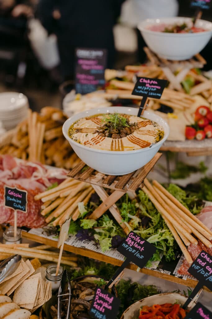 A buffet of bread, vegetables, sliced meat and a large bowl of dip