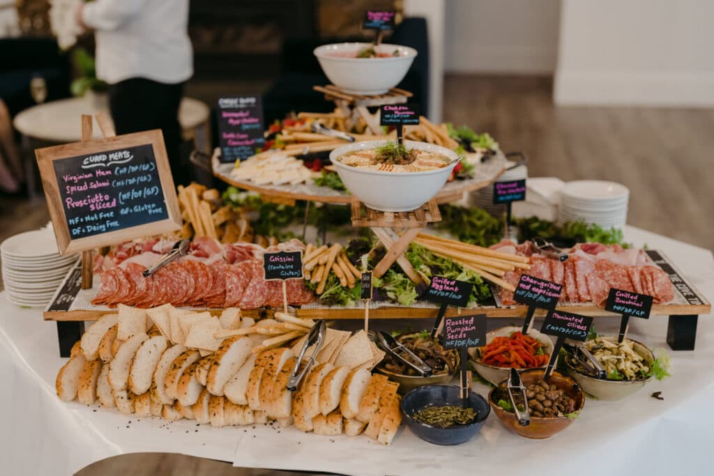 A buffet spread of bread, sliced meats, vegetables and dips