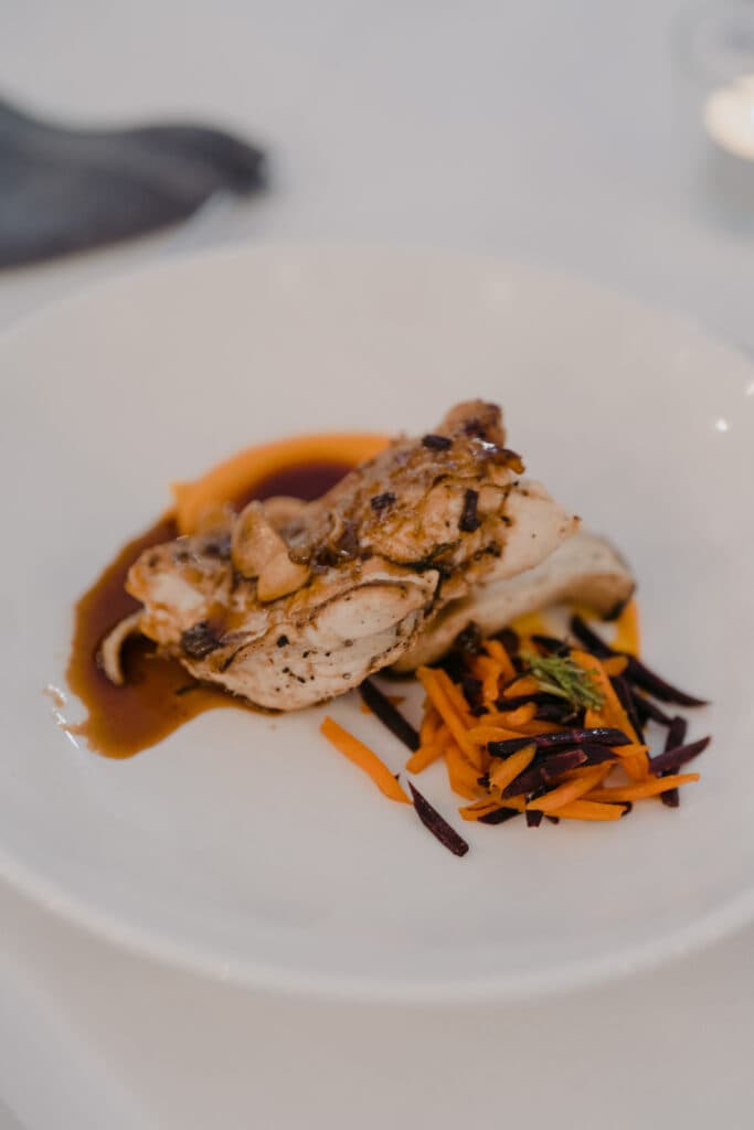 Roasted meat and vegetables with sauce on a white plate