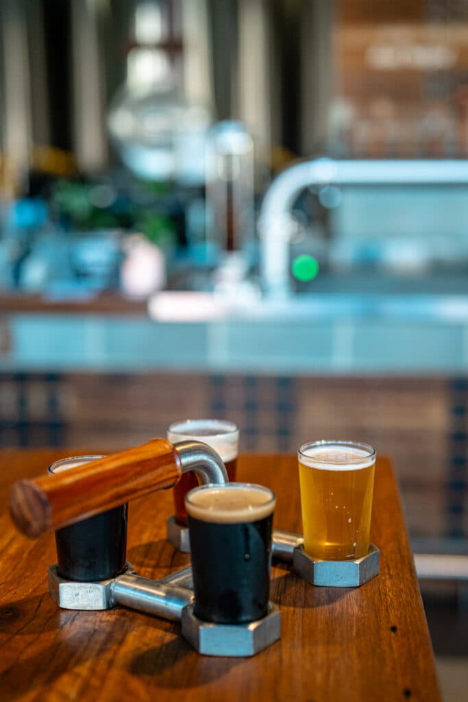 A selection of small beer glasses on a wooden tasting paddle