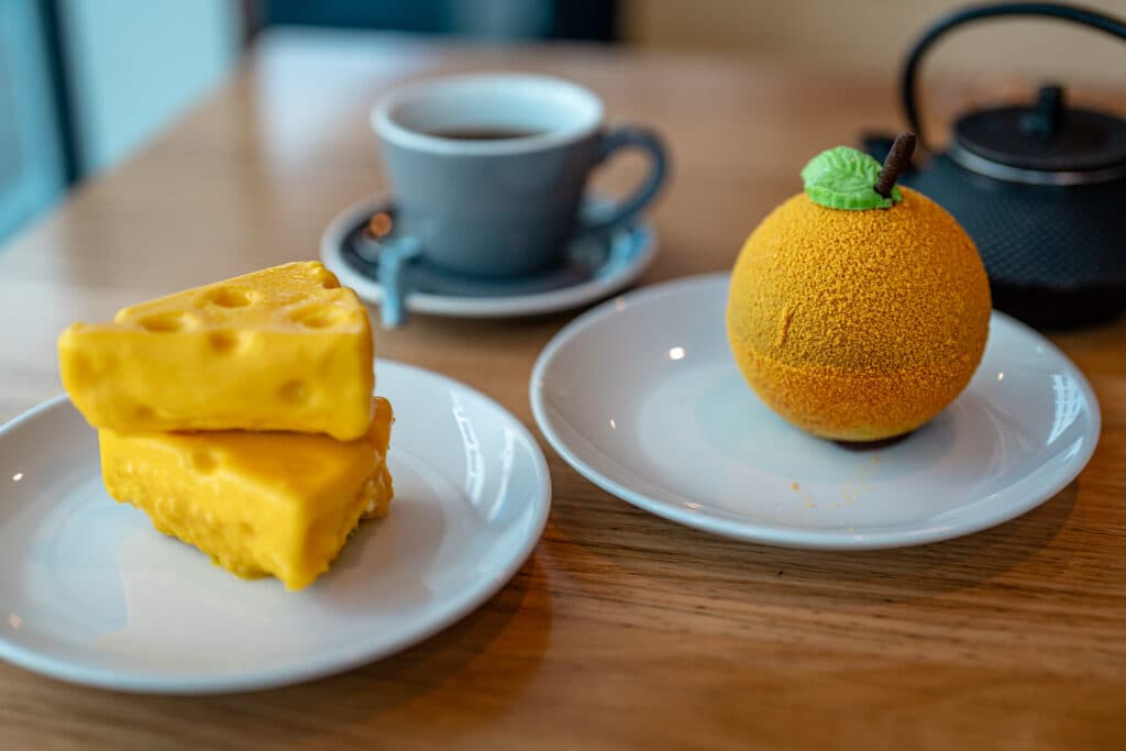 Two yellow desserts beside a cup of coffee