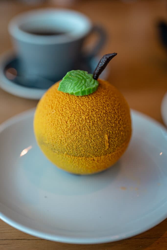 A yellow pear-shaped dessert on a white plate