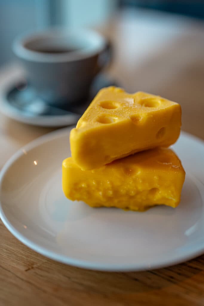 Two yellow cheese-shaped desserts on a white plate