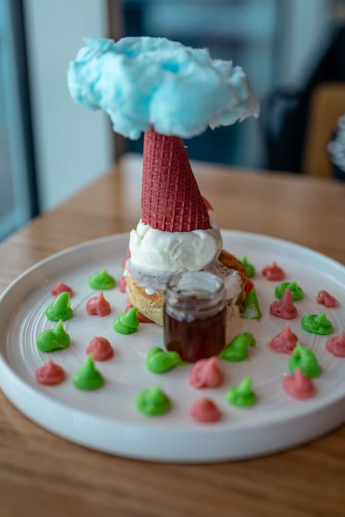 A dessert topped with an inverted cone and blue cotton candy