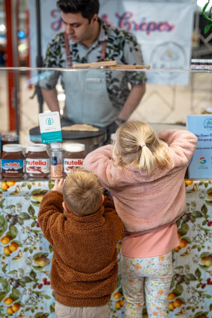 Two children watching a person cook behind a shop window
