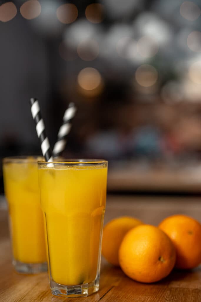 Two glasses of orange juice with striped straws