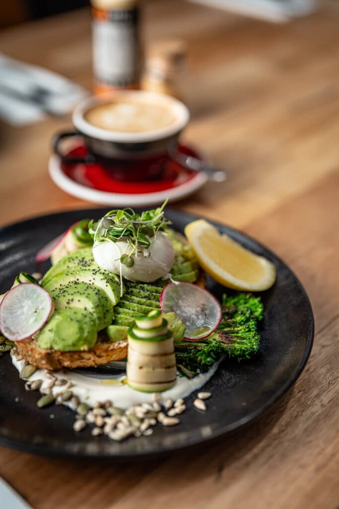 Avocado and poached eggs on toast beside a cup of coffee