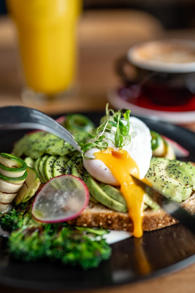 Avocado toast topped with poached eggs and sliced radishes