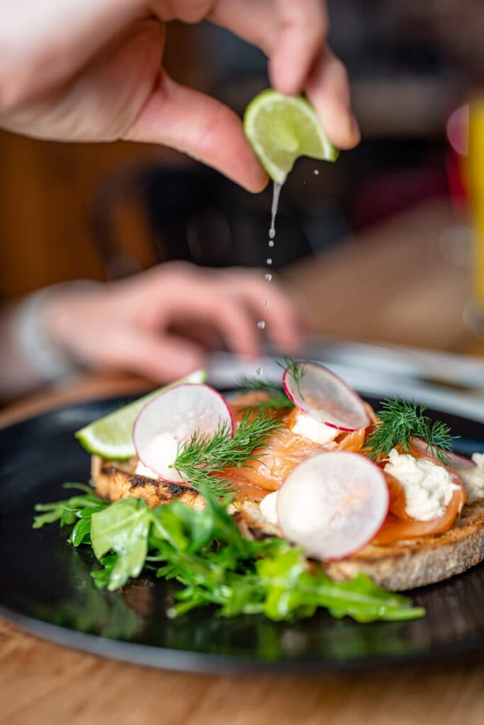 A hand squeezing lime over a plated breakfast
