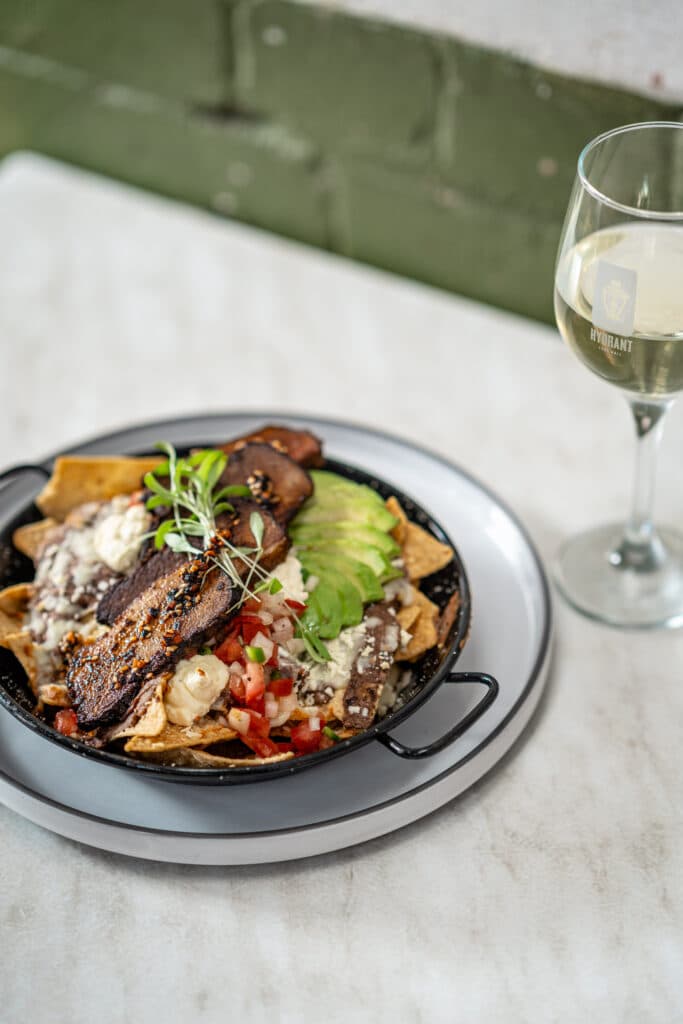 A mixed salad bowl beside a glass of white wine