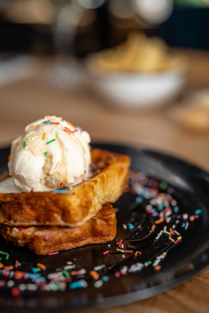 French toast topped with ice cream on a dark plate