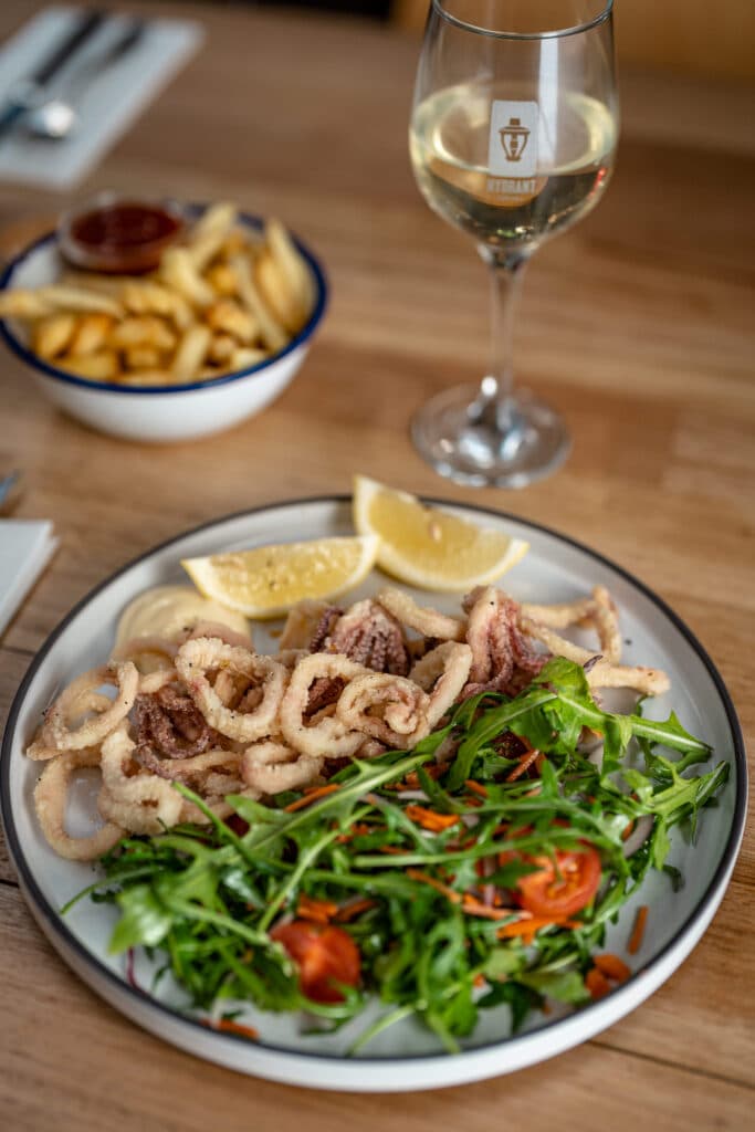 Fried calamari and salad beside a glass of white wine