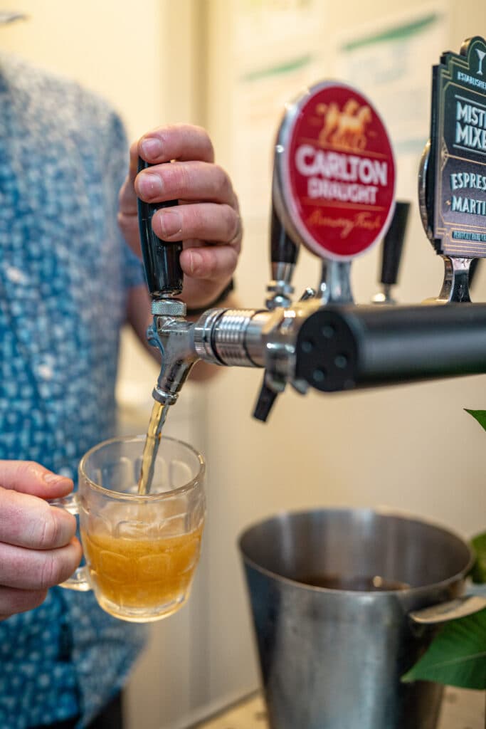 A person pouring beer from a tap into a glass