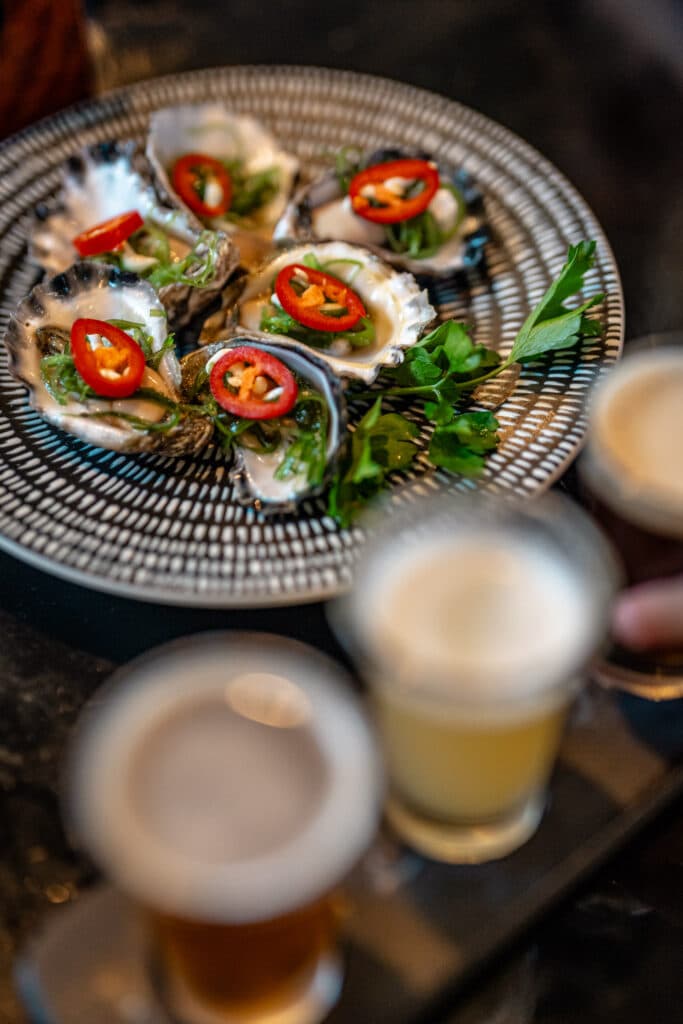 Oysters topped with sliced red chillies on a patterned plate
