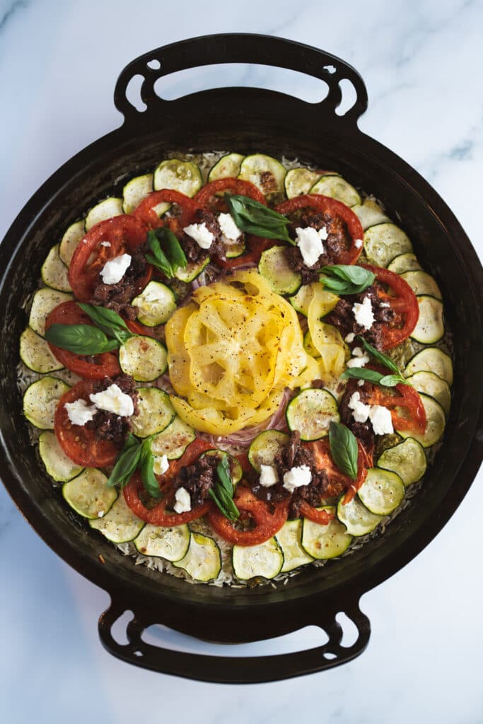 A black pan filled with colourful sliced vegetables and rice
