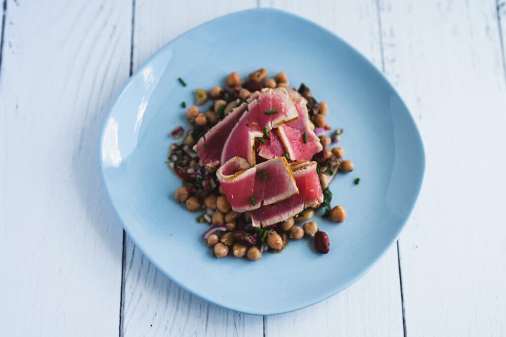 Slices of seared pink fish arranged on a blue plate