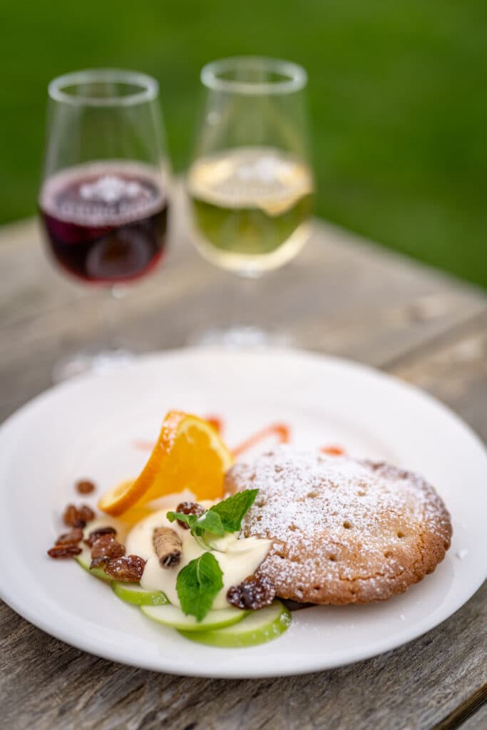A plated dessert beside glasses of red and white wine