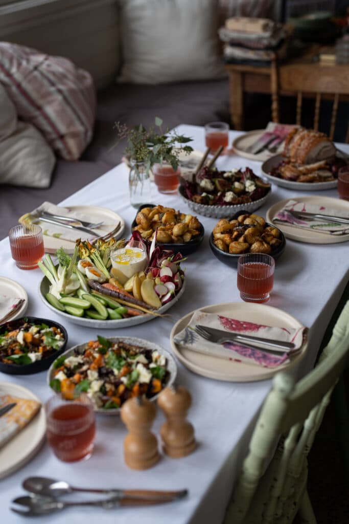 A dining table spread with meat, vegetables and drinks