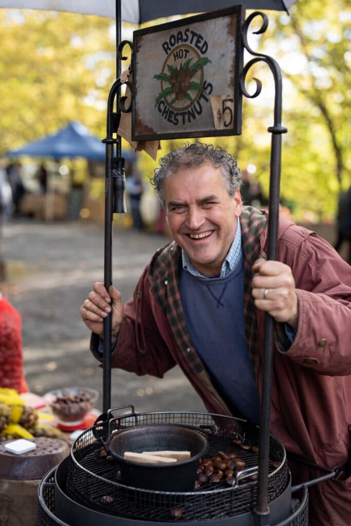 A smiling man standing beside an outdoor cooking pot